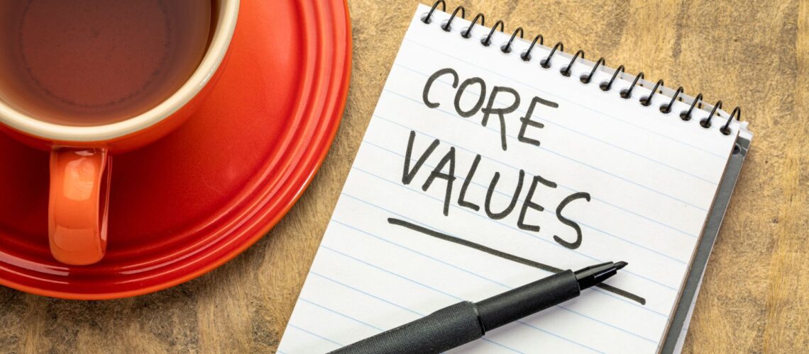 Core values written in notebook with pen and coffee cup representing workplace values development