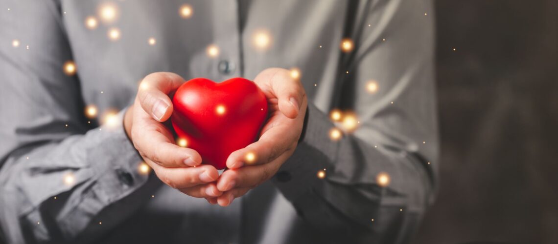 Professional in business suit holding glowing red heart symbolizing heart centred leadership and authentic leadership development training