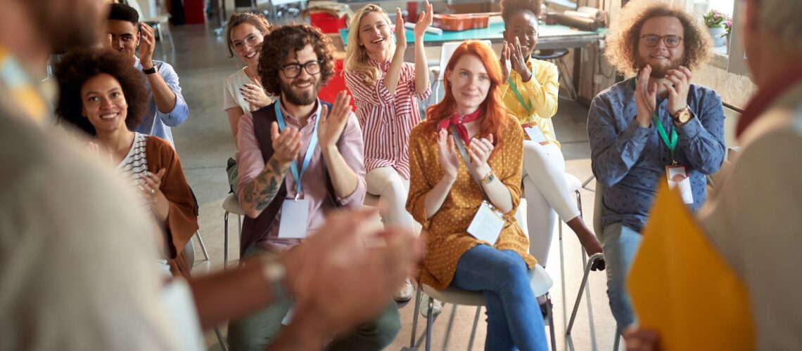 Diverse group of professionals applauding during leadership development training session showing engagement and authentic leadership principles in action