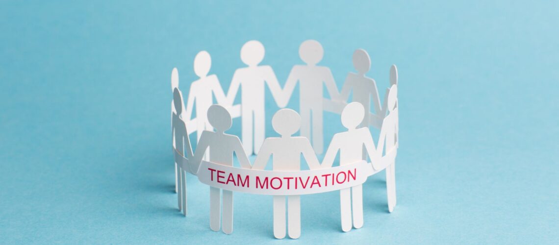 Paper cutout figures holding hands in circle with team motivation banner representing unified workplace collaboration