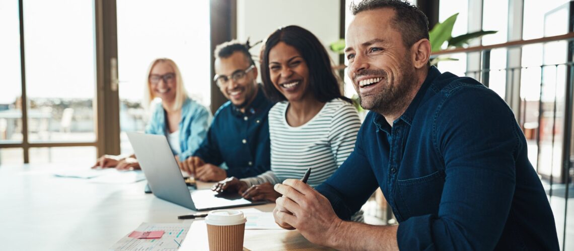 Engaged diverse team smiling during productive meeting demonstrating effective workplace motivation and employee engagement
