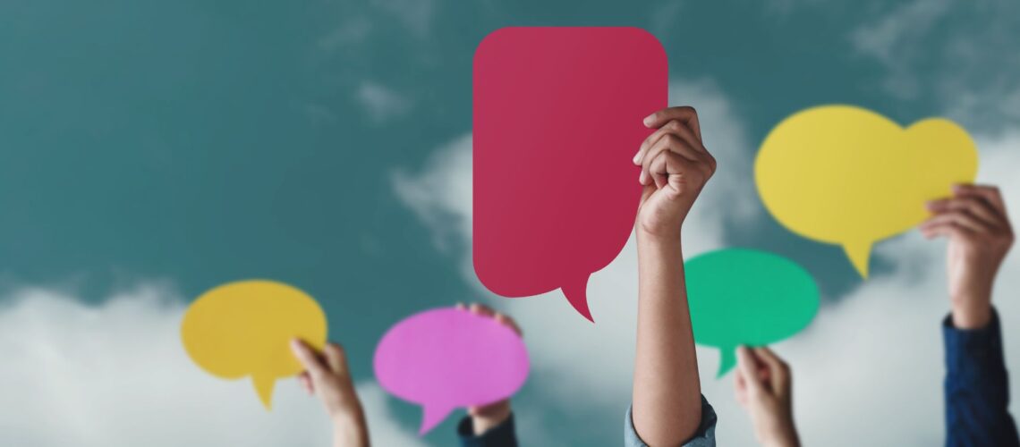 Hands holding colorful speech bubbles representing diverse voices in difficult conversations