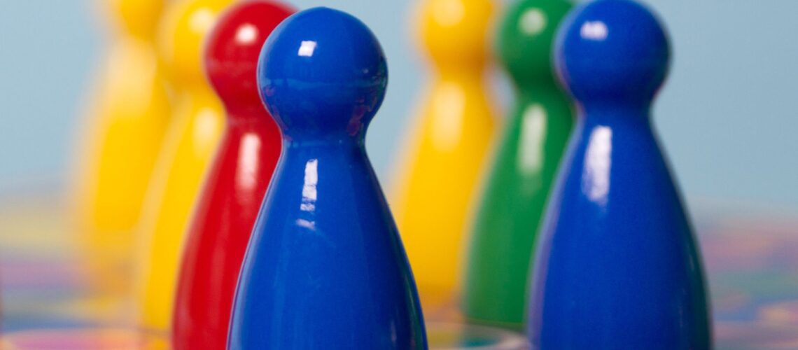 Colourful game pieces representing different Insights Discovery personality types - red, yellow, green and blue energies in workplace teams
