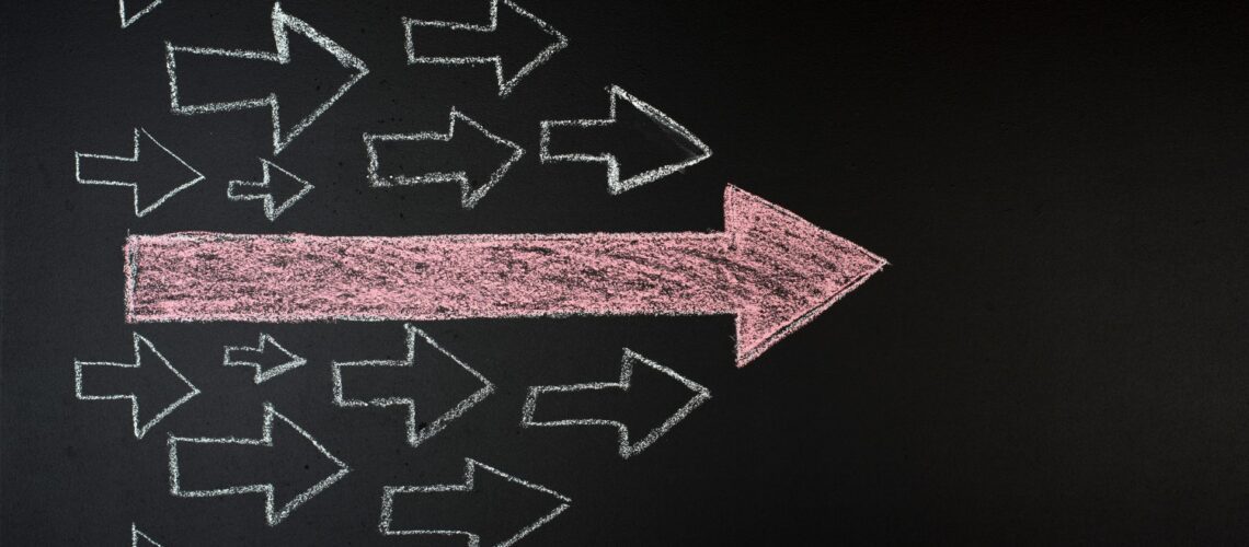 Chalk arrows on blackboard with one large arrow leading the way, symbolising leadership and direction