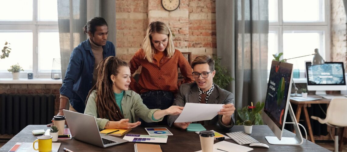 Diverse professional team collaborating around laptop demonstrating effective delegation strategies in modern office environment