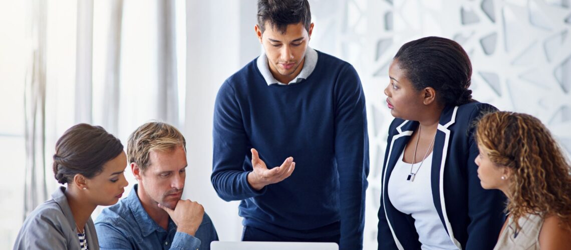 Professional team leader engaging with diverse colleagues in collaborative workplace discussion demonstrating positive behavioural leadership techniques