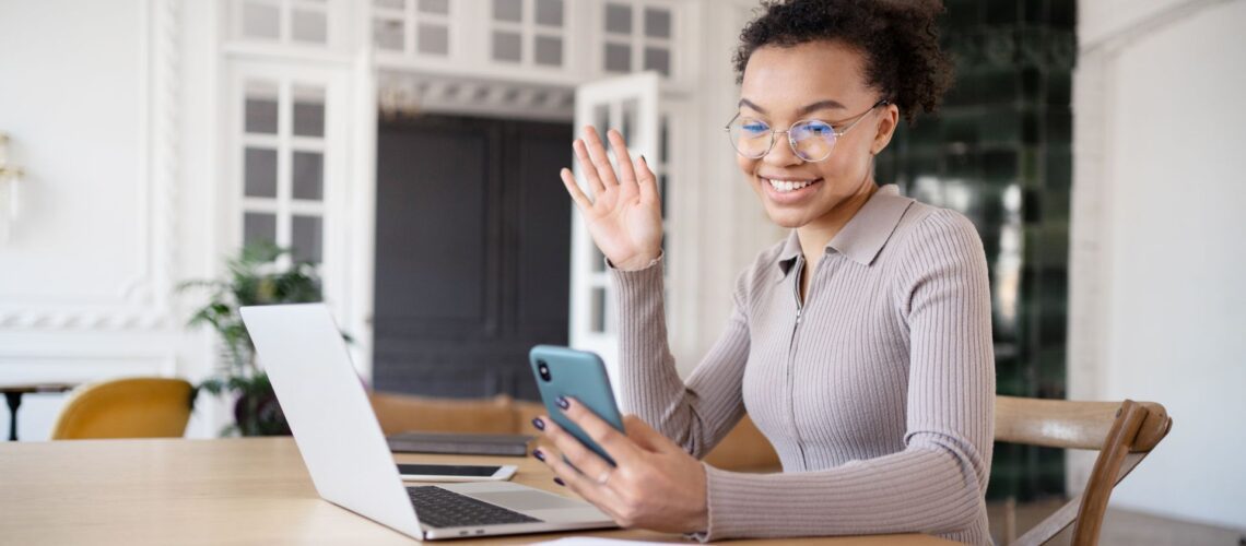 Young Generation Z professional using smartphone and laptop for digital communication in modern office