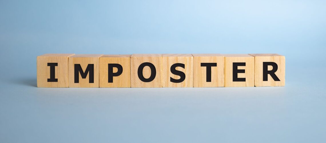 Wooden letter blocks spelling out IMPOSTER on clean background representing imposter syndrome concept