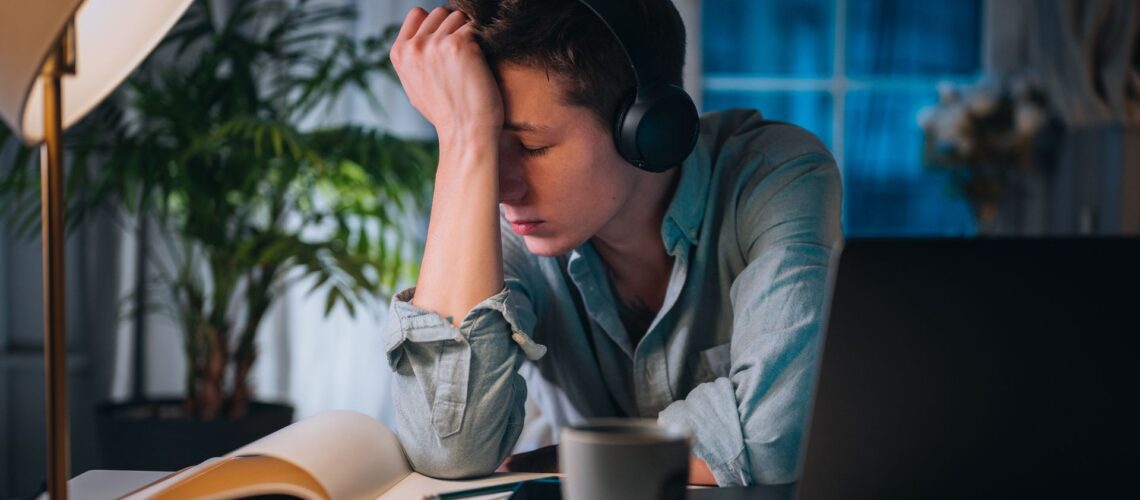 Young professional experiencing stress and self-doubt whilst working at desk, representing imposter syndrome challenges