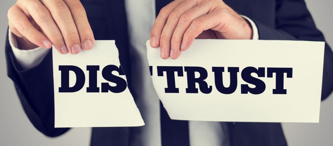 Business professional tearing apart distrust sign symbolising overcoming workplace trust barriers