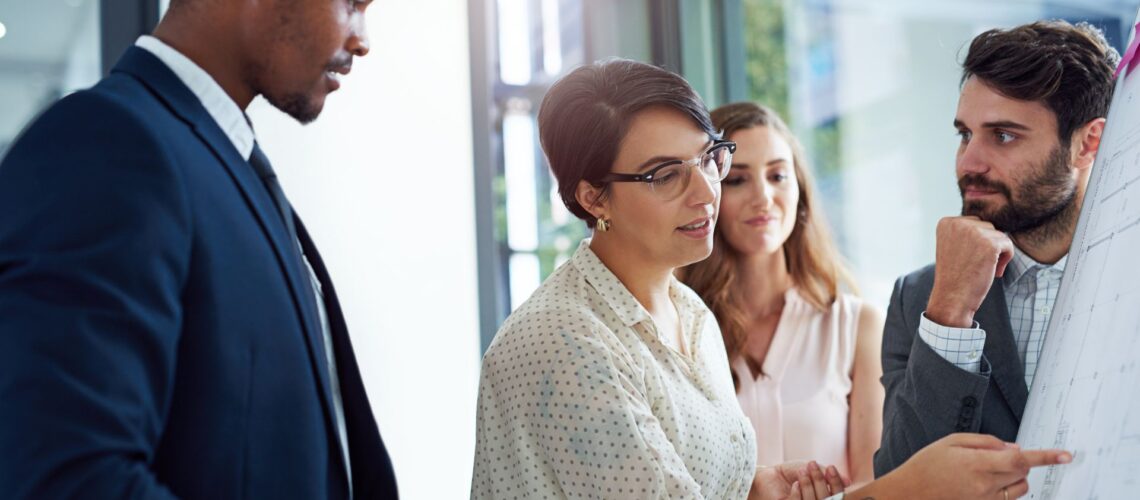 Diverse professional team collaborating in office with woman leading discussion demonstrating ownership mindset